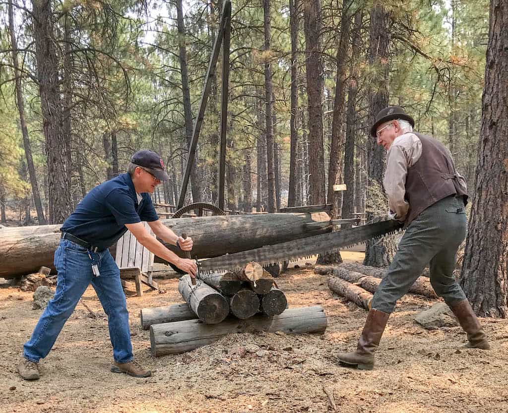 Two visitors trying out cutting logs at the High Desert Museum in Bend, Oregon.