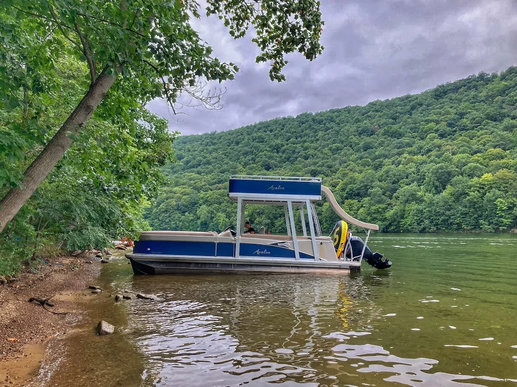 A pontoon boat with a slide on the back that is available for rent from Lake Raytsown Resort in Entriken, Pennsylvania.