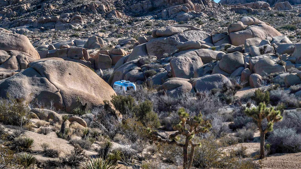 An Airstream hidden among the boulders at a campground in Joshua Tree National Park.
