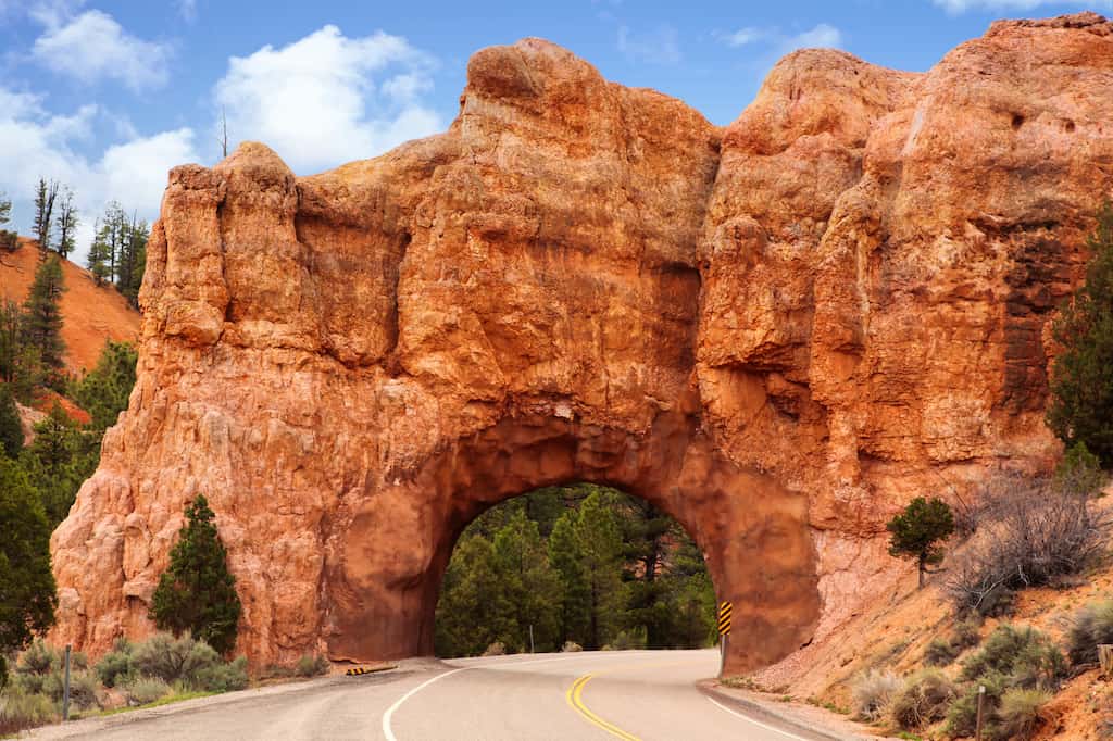 Red stone arch on highway 12 to Bryce Canyon, Utah, USA. This man-made tunnel has been cut through the rock and the road runs through Dixie Forest.