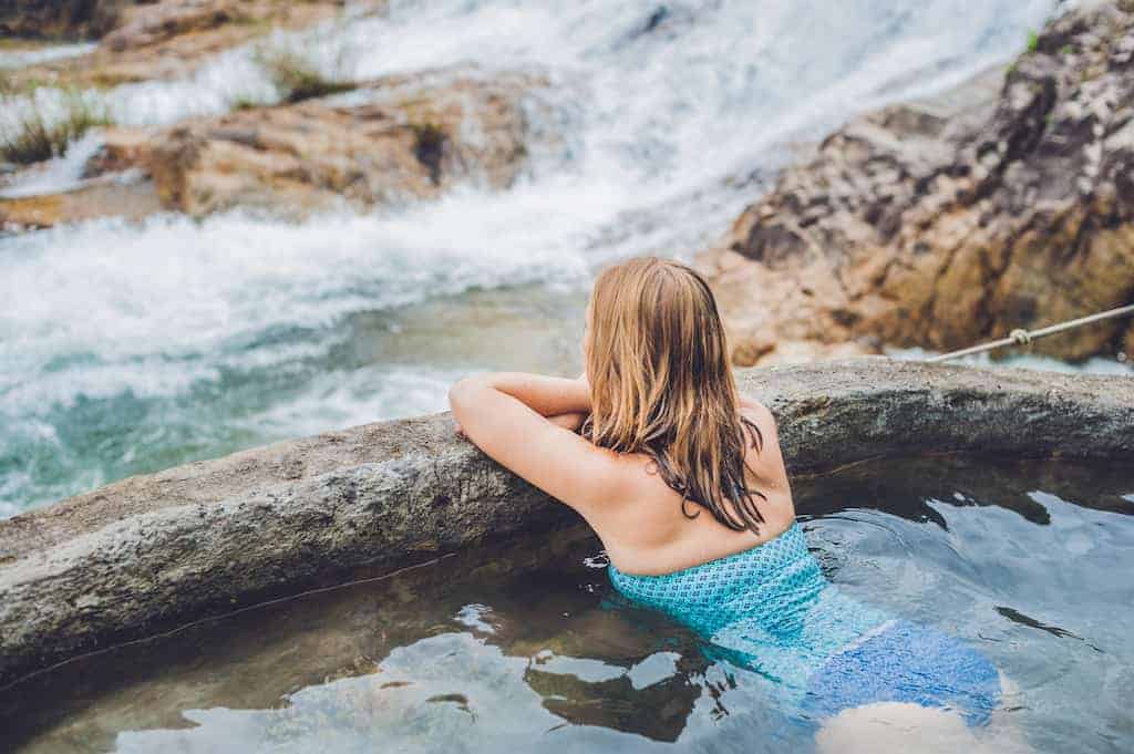 A woman relaxes in a natural hot springs in the winter. 