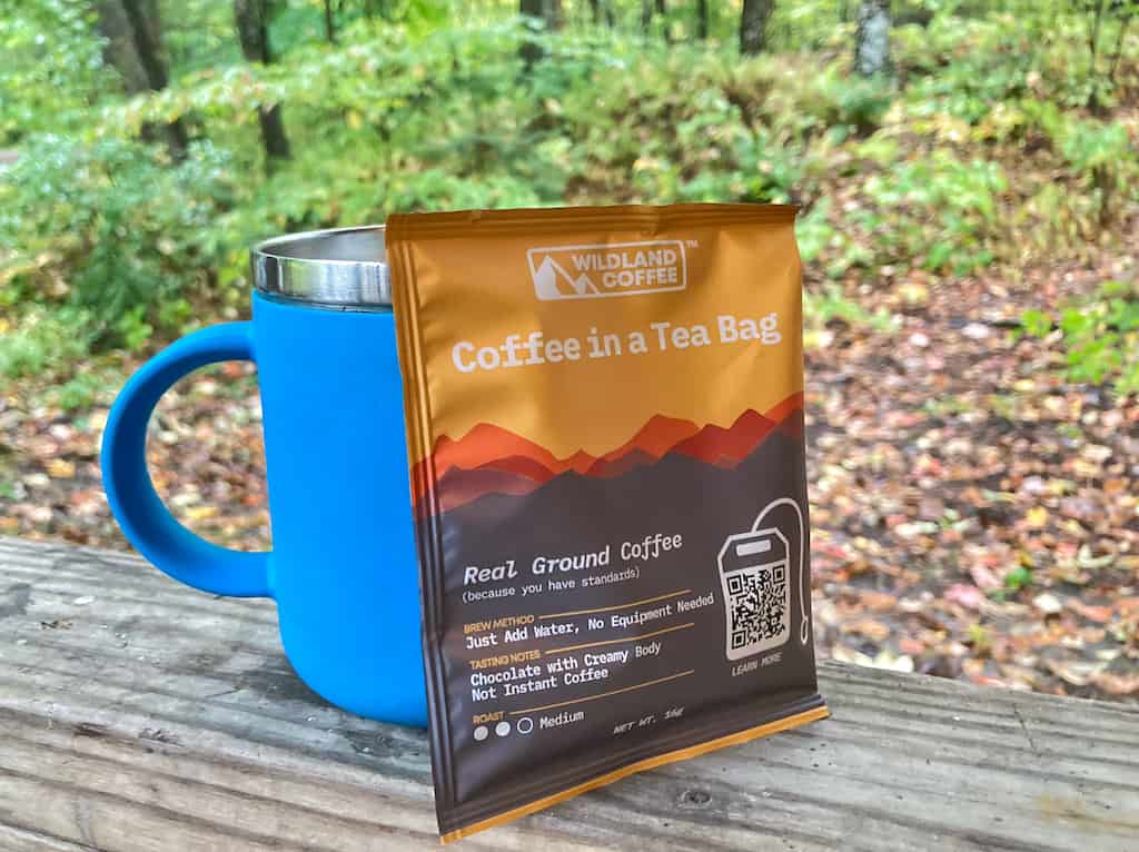 A bag of Wildland Coffee sits next to a camping coffee mug.