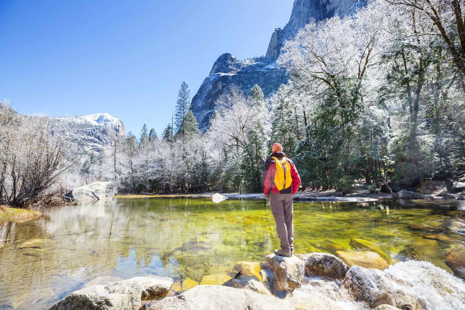 A man stands next to an alpine lake in Yosemite National Park in California.