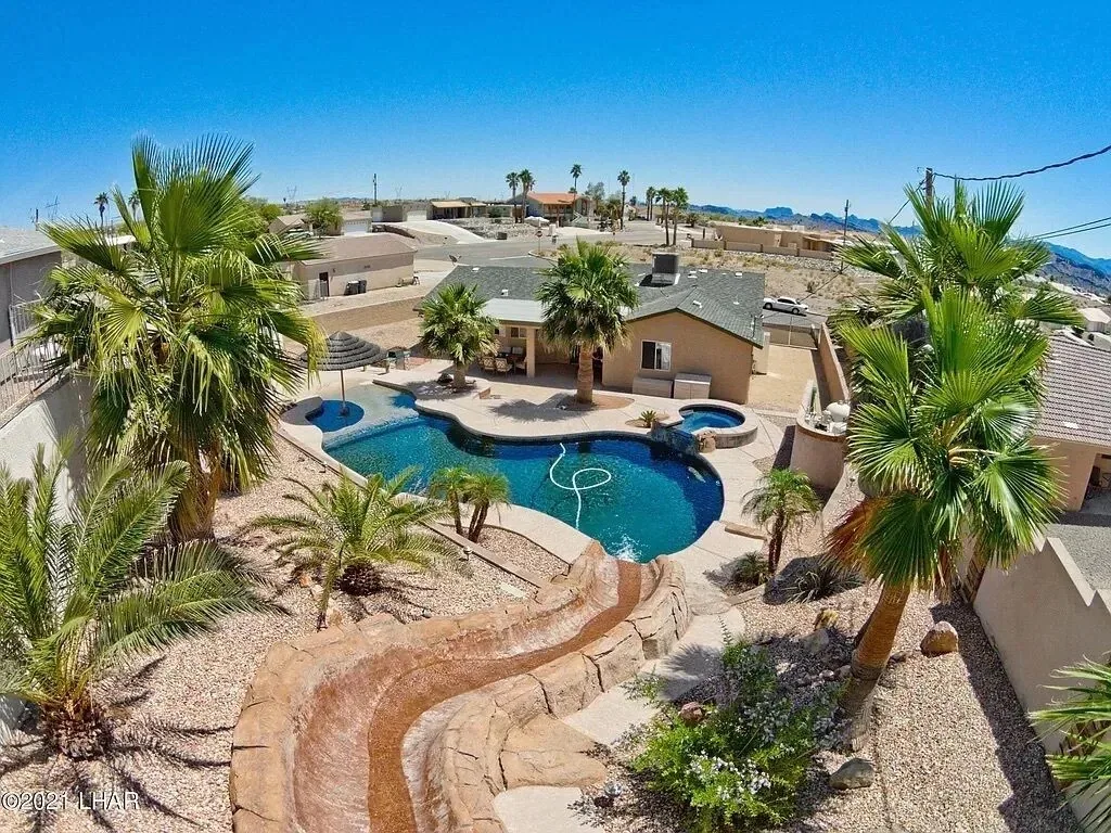 An aerial view of a vacation rental in Lake Havasu City, Arizona with a pool, hot tub, and water slide. Photo credit: VRBO