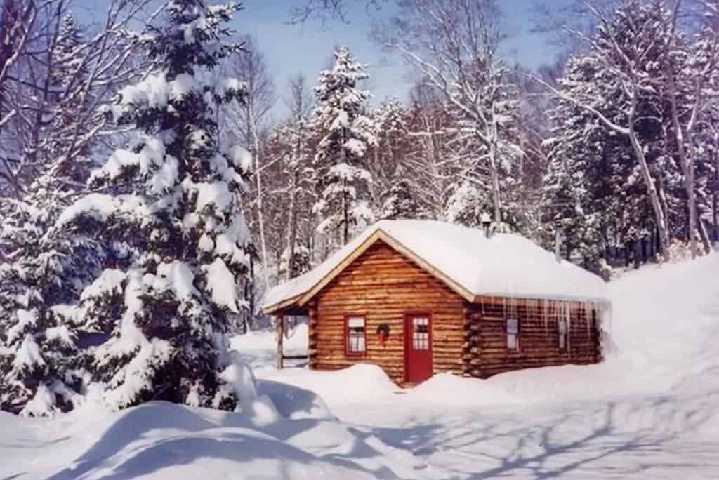 A log cabin in a snowy field in Vermont.