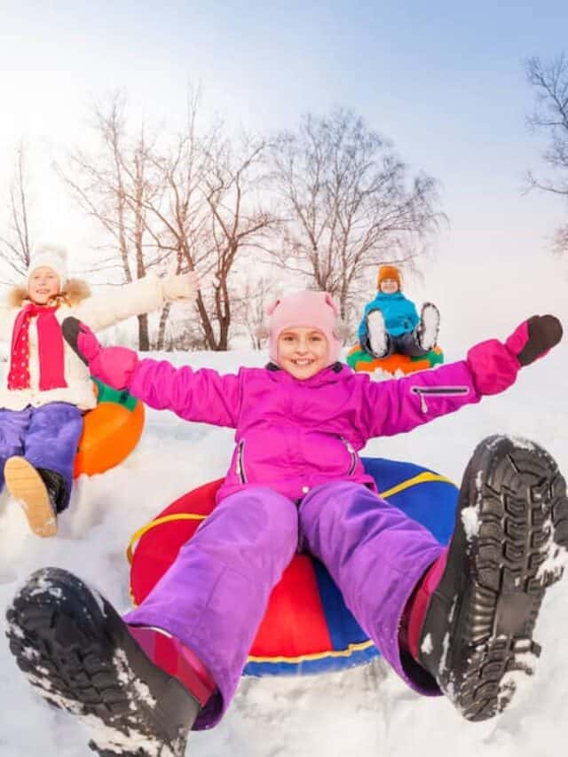 Several kids slide down a snow tubing hill on their winter vacation.
