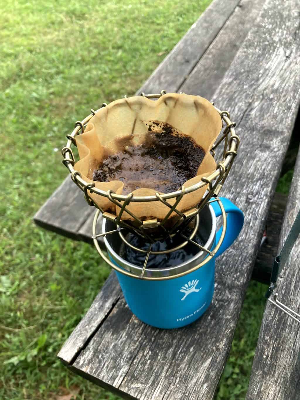 A blue camping mug with a small drip filter on top for making camping coffee.