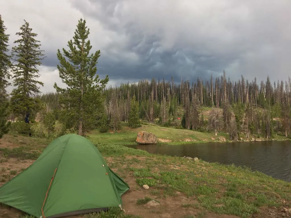 A small green tent on the shore of Brooks Lake in Pinnacles Campground, Wyoming.