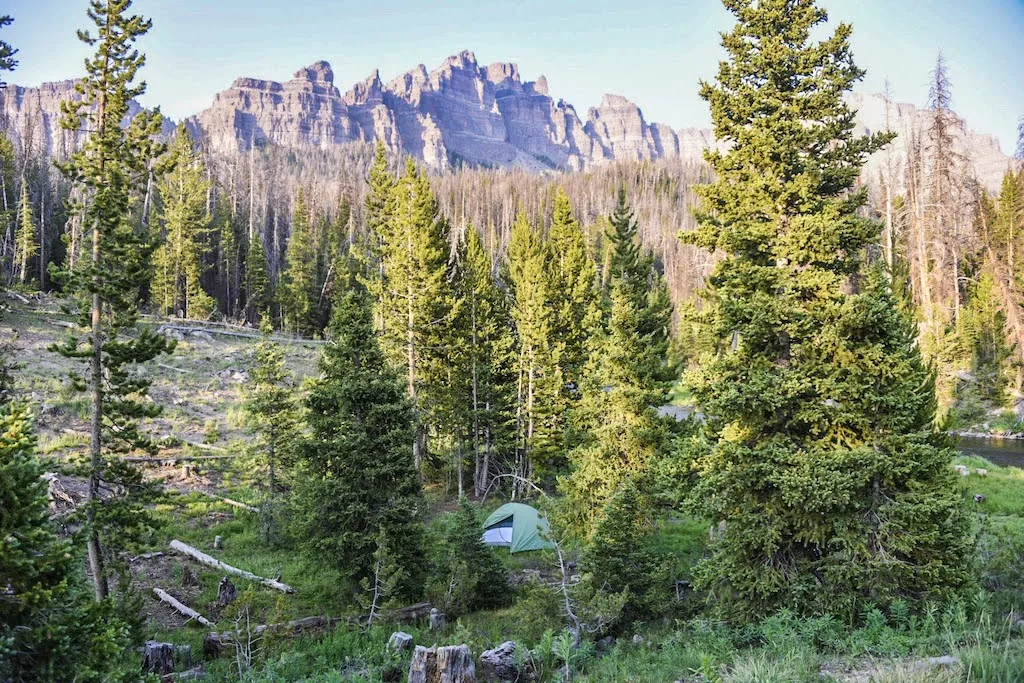 A small green tent at the base of Pinnacle Butte in Pinnacles Campground in Shoshone National Forest, Wyoming.