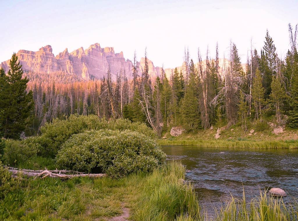 A sunset view of Brooks Lake Creek and Pinnacle Butte from Pinnacles Campground in Wyoming.