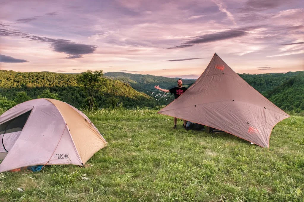 a small tent and a kitchen tarp covering a picnic table at a campground.