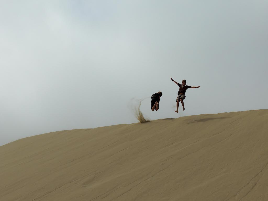 Two kids playing in the sand at Oregon Dunes National Recreation Area. 