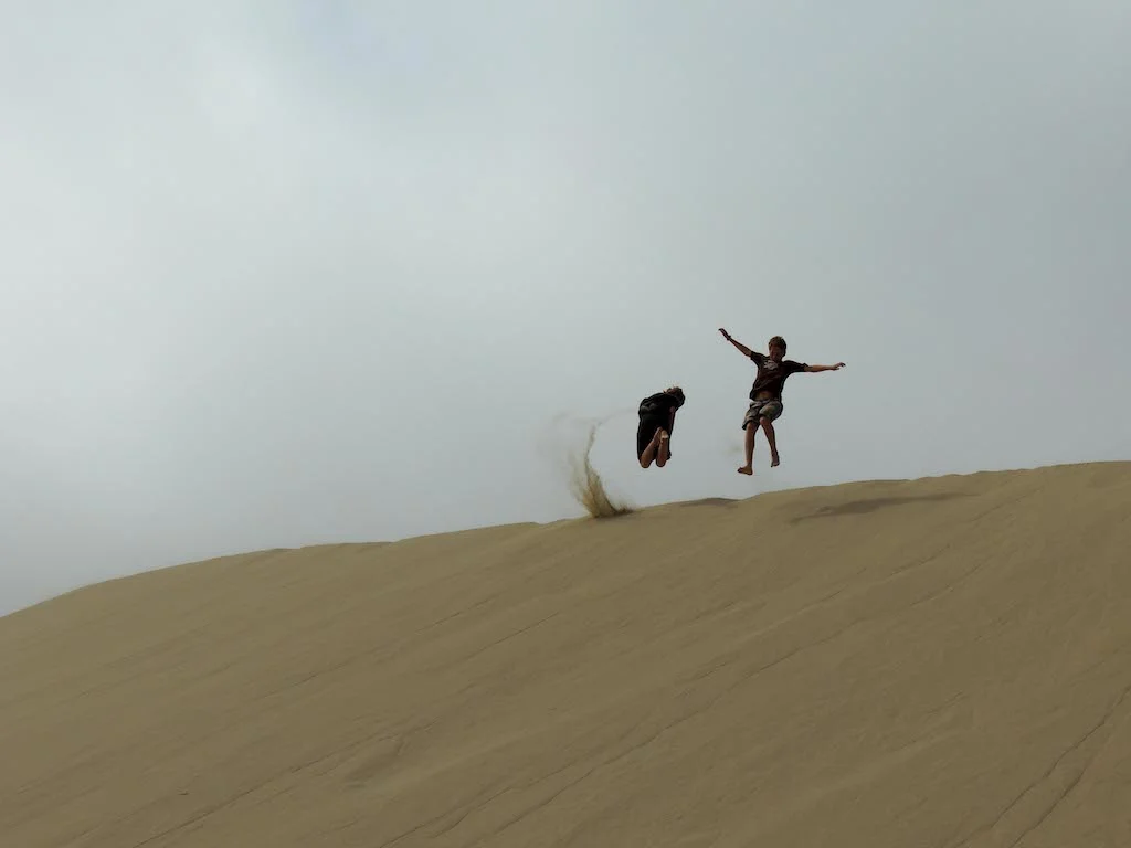 Two kids playing in the sand at Oregon Dunes National Recreation Area. 