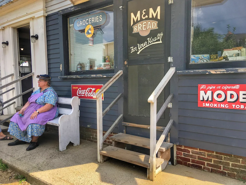 A reenactor sits outside a historic store at Strawbery Banke Museum in Portsmouth, NH.