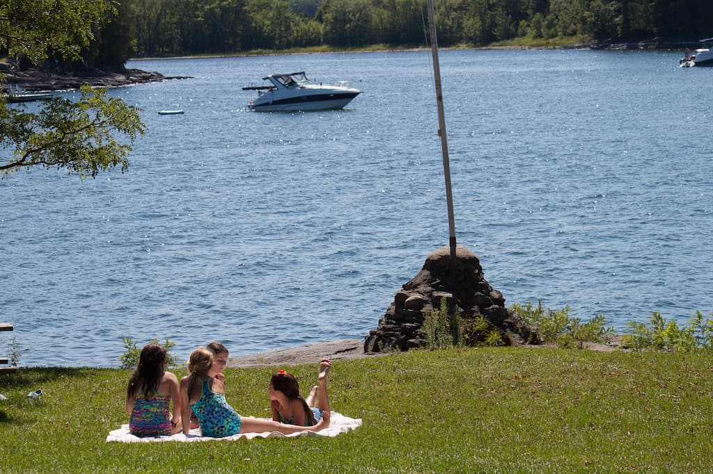 Several kids sit on a blanket having a picnic on the shores of Lake Champlain in Vermont.
