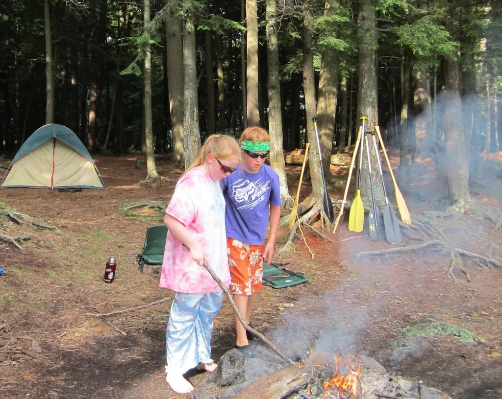 Two kids tend a campfire in the Adirondacks of New York.