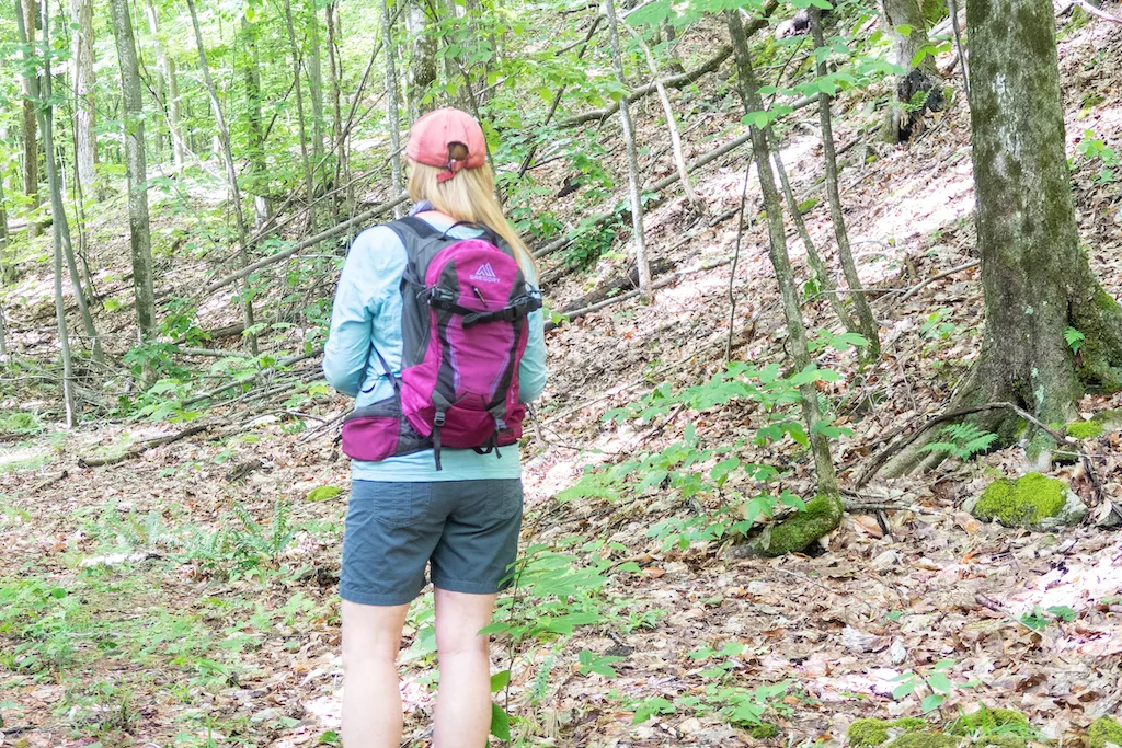 Tara stands in the woods wearing her favorite daypack from Gregory. 