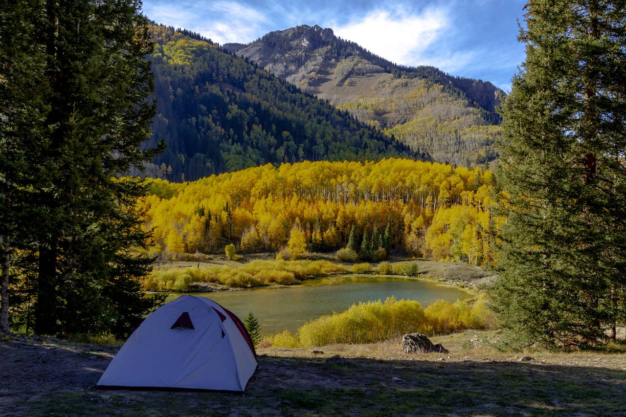 A single tent set up near a lake in Colorado in the fall.
