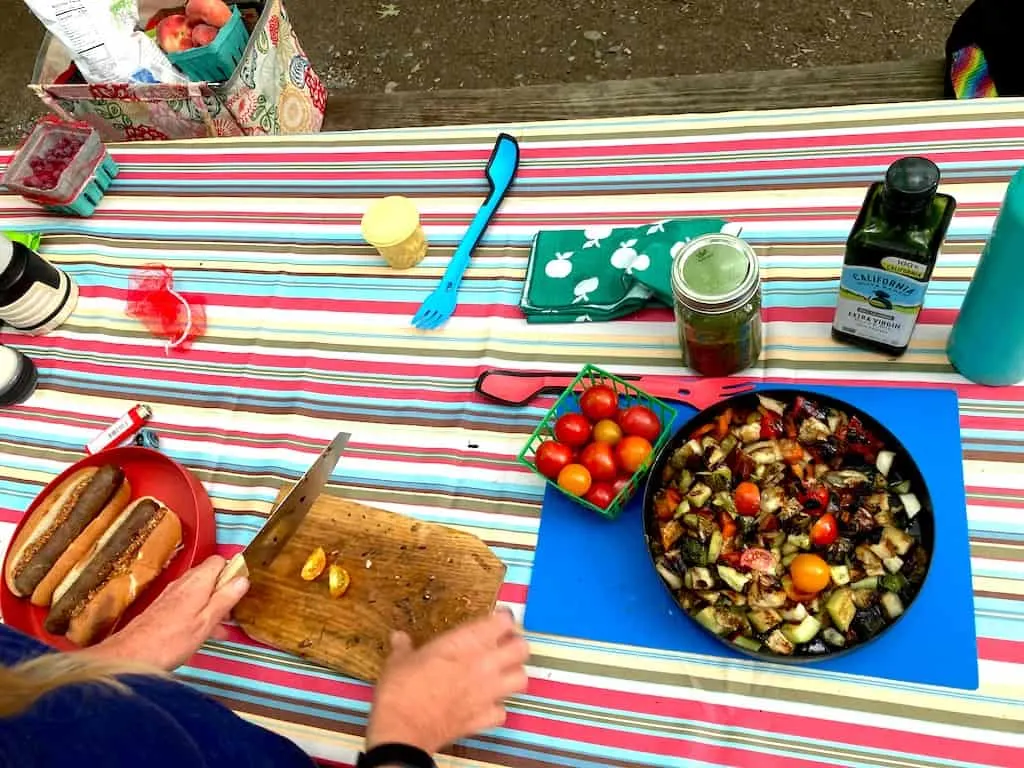 Cooking grilled ratatouille on a striped tablecloth while camping.