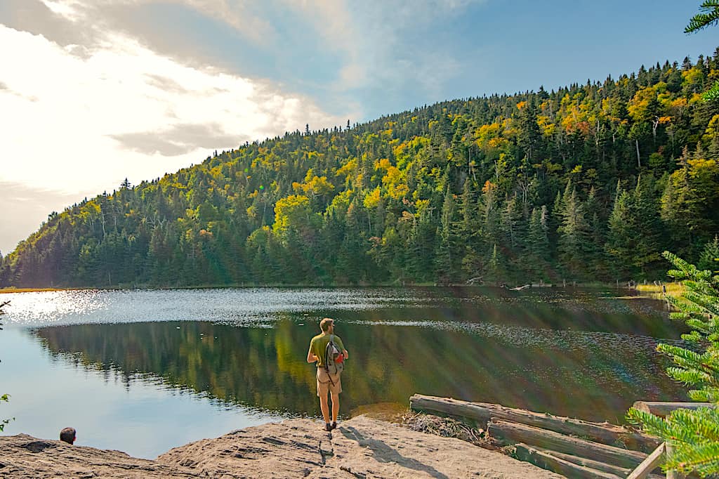 A man stands on the edge of Lake Spruce in Quebec.