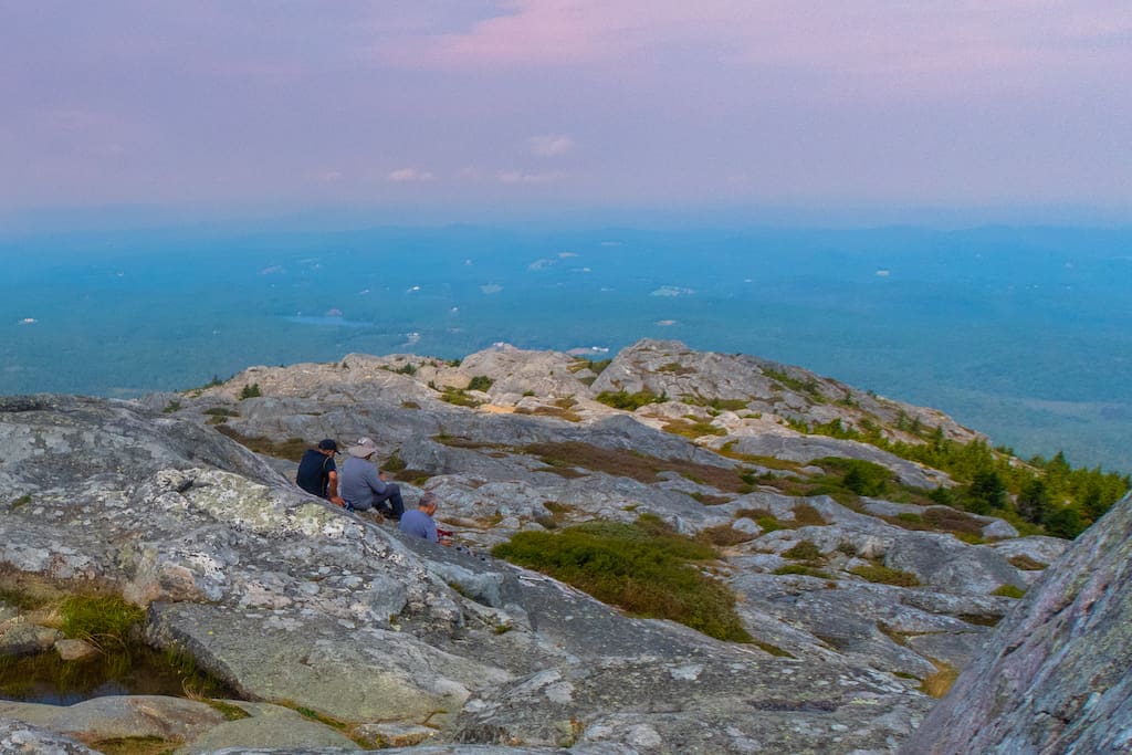 Three hikers sit on the summit of Mount Monadnock in New Hampshire. 