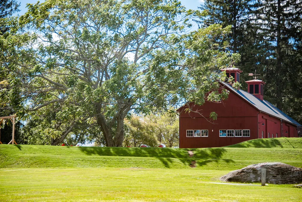 A large red barn shaded by a beautiful black walnut tree at Balderdash Cellars in Richmond, Massachusetts. 