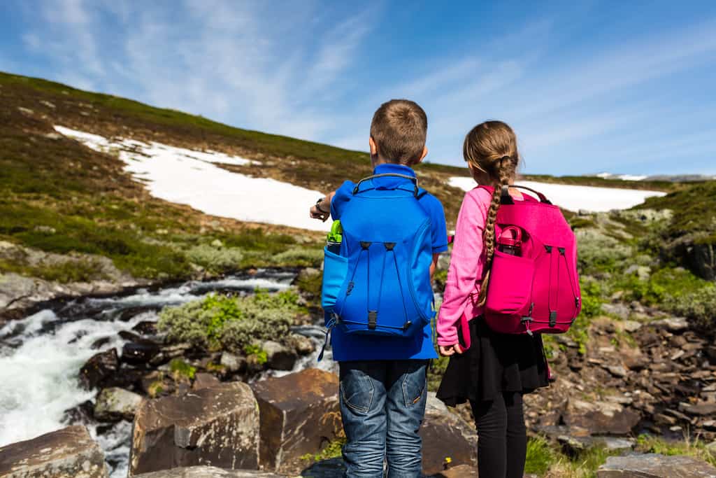 Two kids wearing daypacks on a winter hiking trip. 
