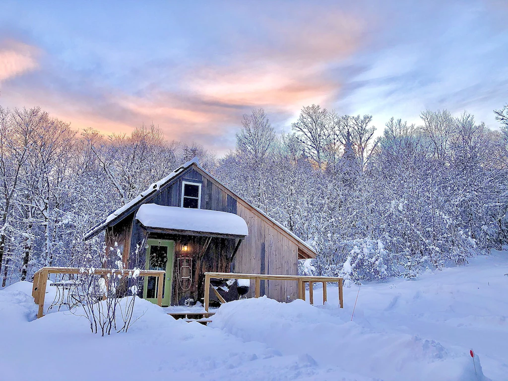 A rustic cabin covered with snow in Vermont. 