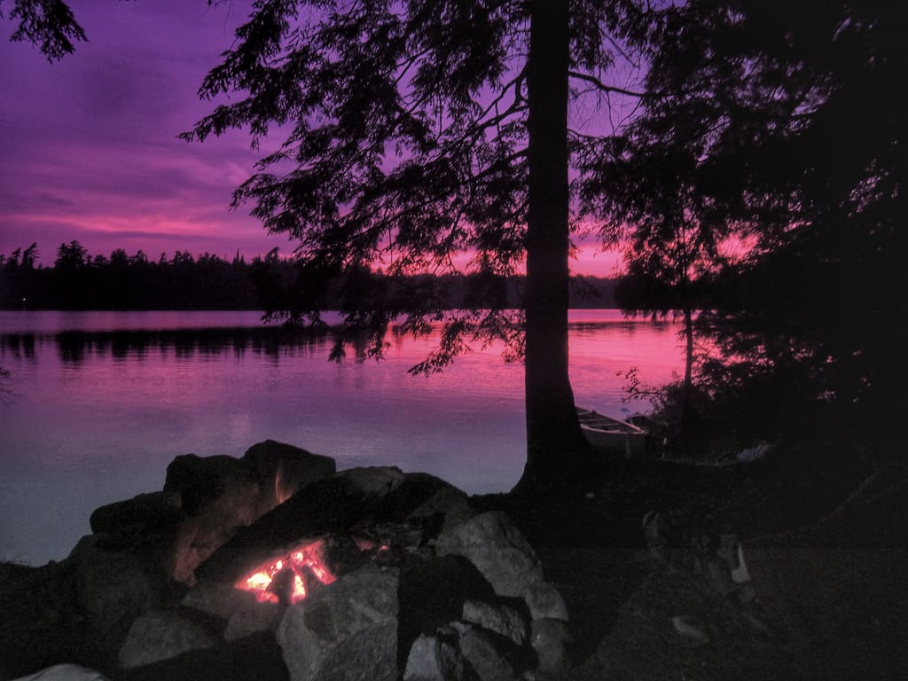 Sunset campfire on a clear lake.