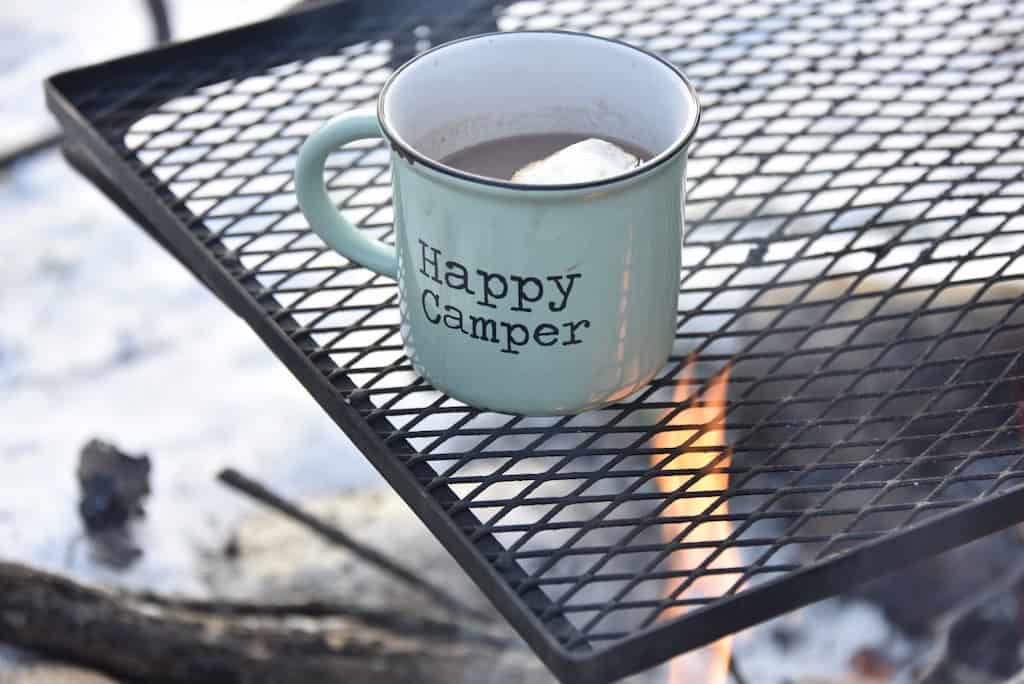Happy Camper mug sitting over a campfire.