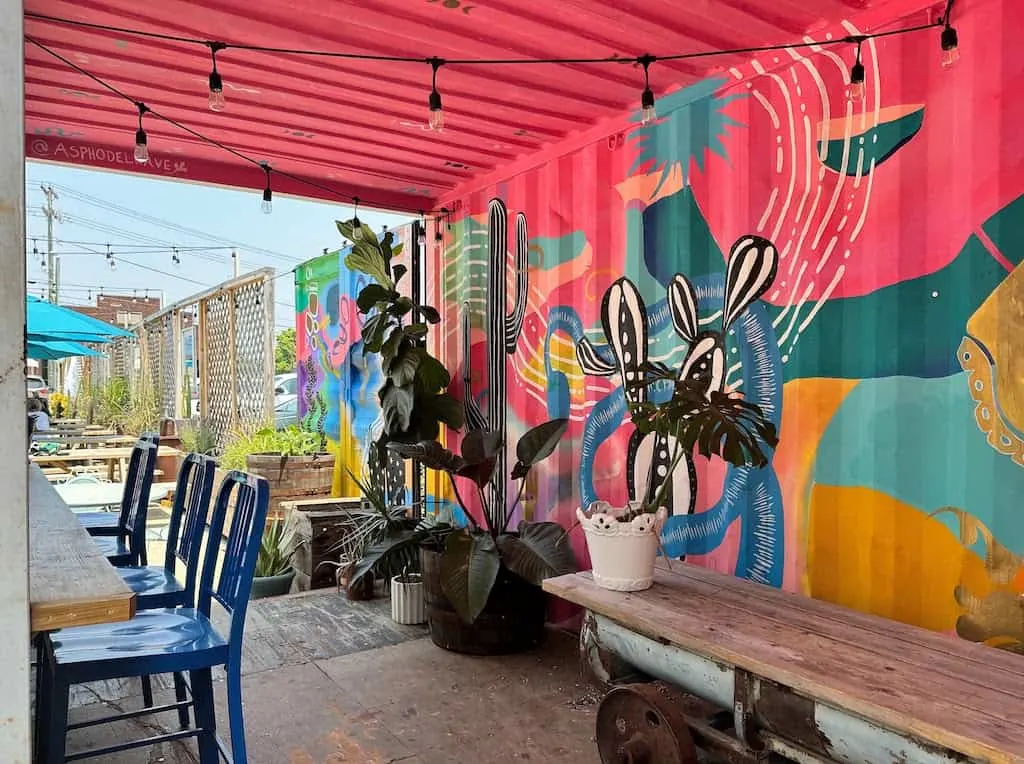 A small part of the outdoor patio at Golden Cactus Brewing with a bright cactus mural on the wall.
