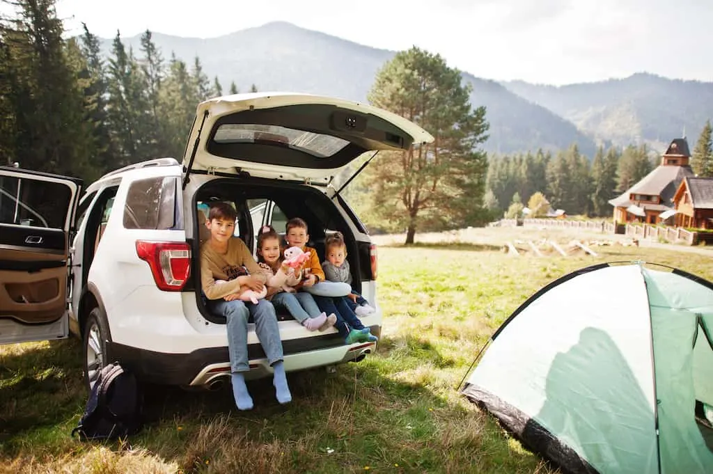 Four kids sitting in back of the family car on a family road trip.