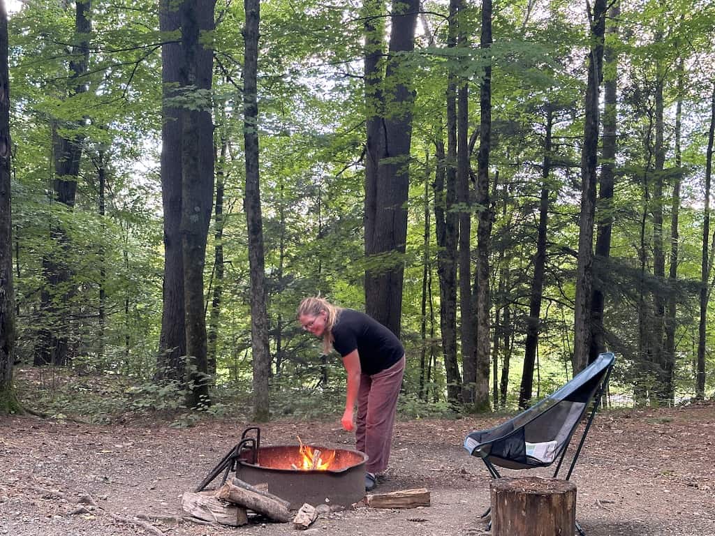 Tara adding wood to a campfire at a campground in Vermont. 