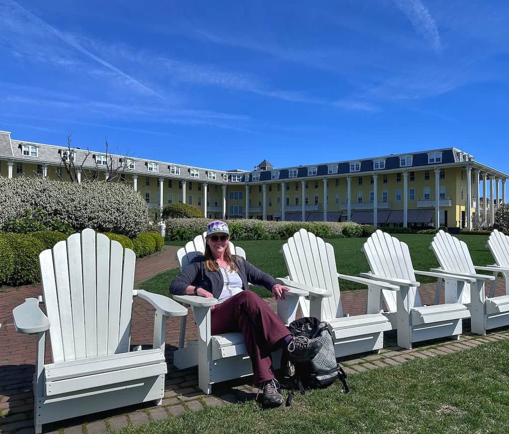Tara sitting in one of several white Adirondack chairs in front of Congress Hall.