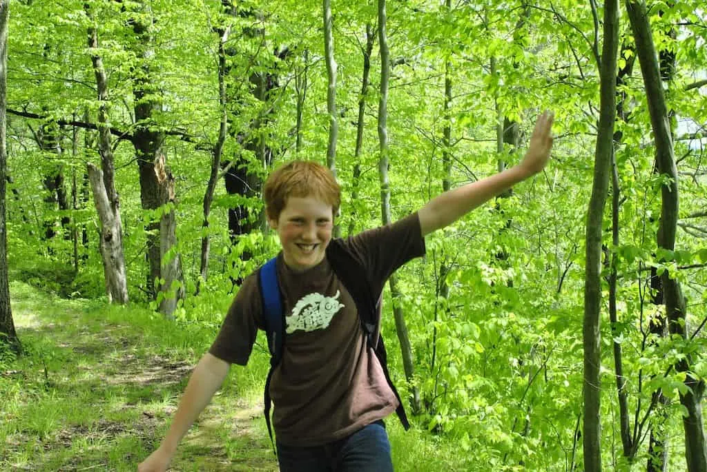 Gabe hiking through a green forest. 