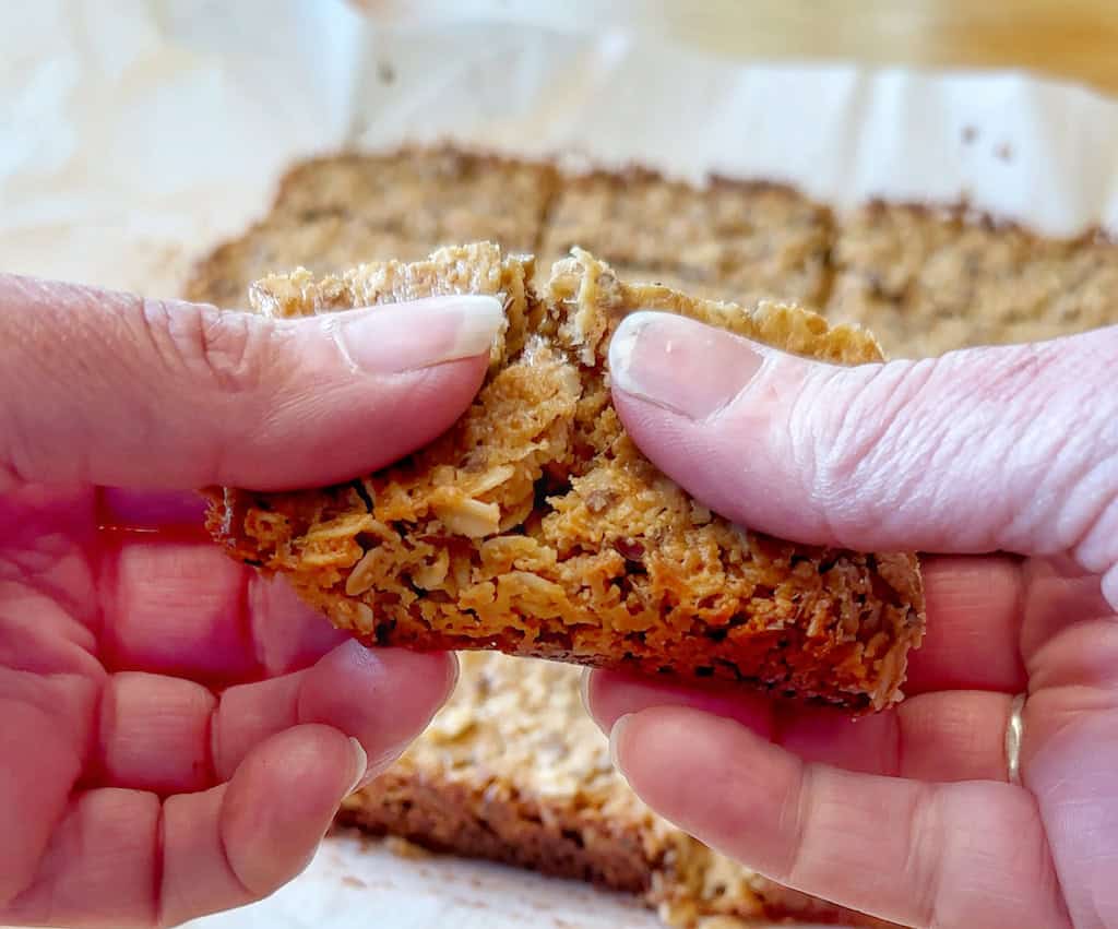 Two hands pulling apart one of the granola bars before eating. 