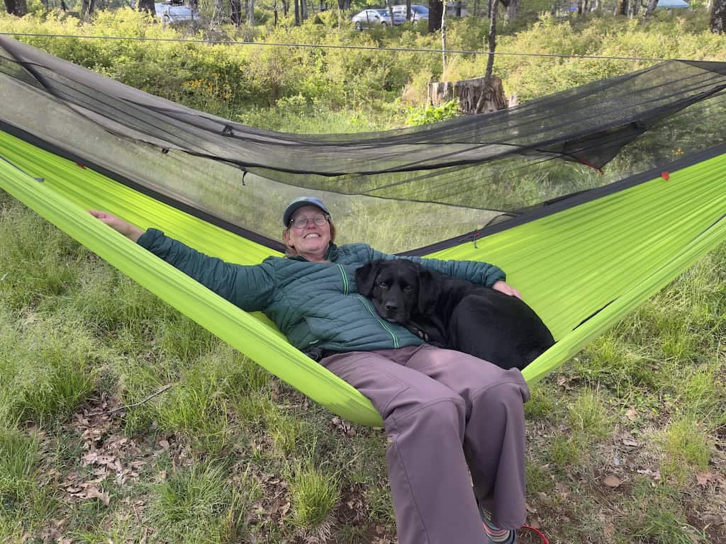 Tara and black lab, Malinda cuddle in a green hammock. 