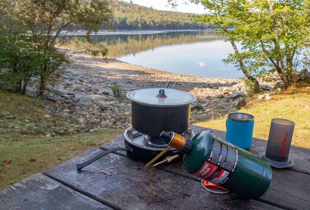 A campstove set up next to a lake. 