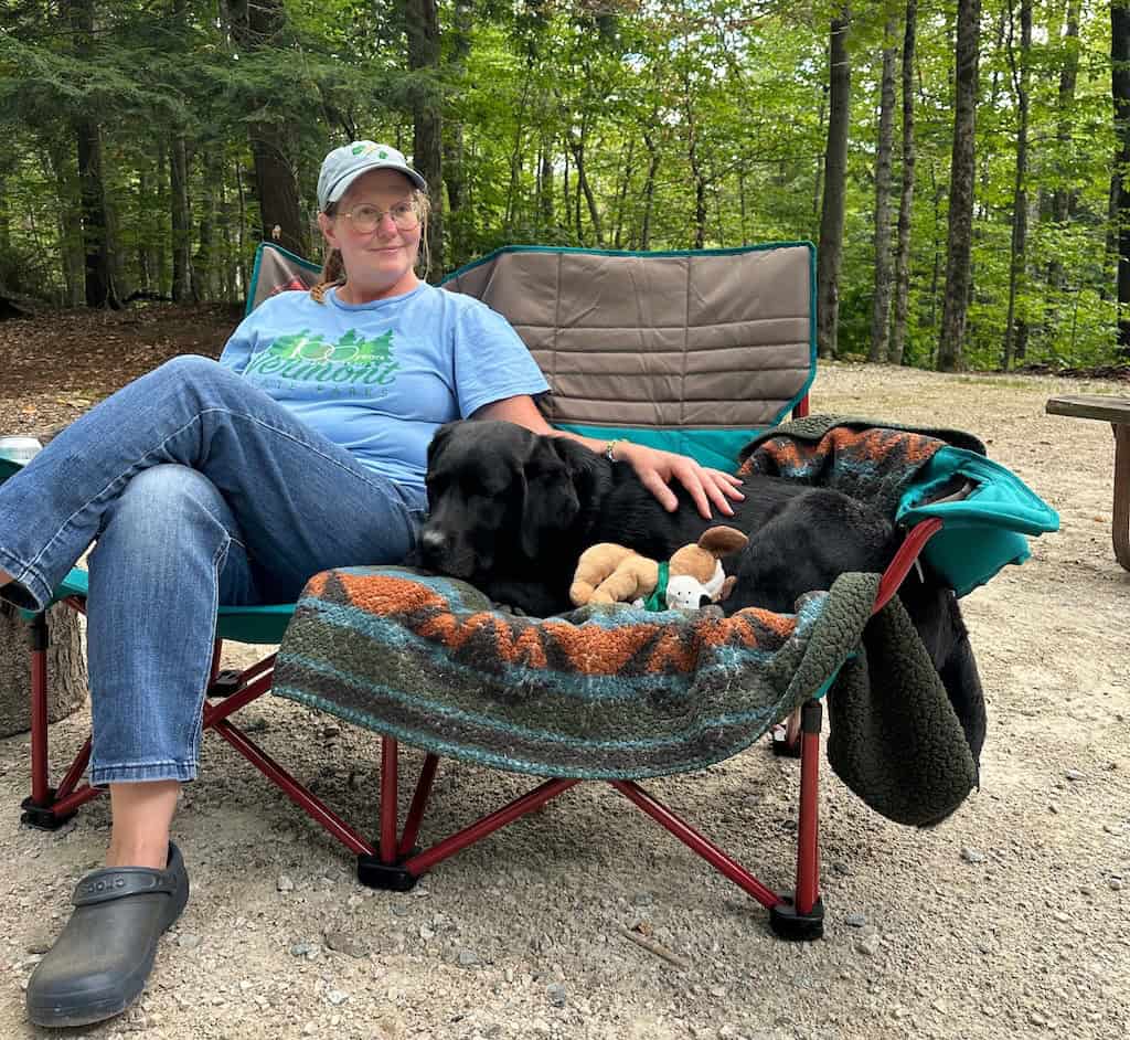 Tara and a black lab sitting on a camping loveseat. 